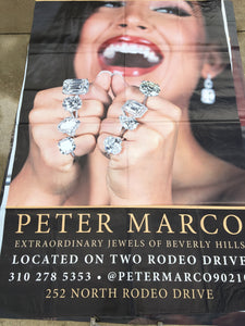 A vinyl billboard for Peter Marco in Beverly Hills featuring a woman with diamond rings on every finger. 